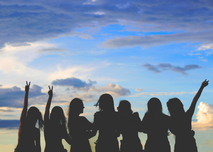 Silhouettes of women against a cloudy sky.