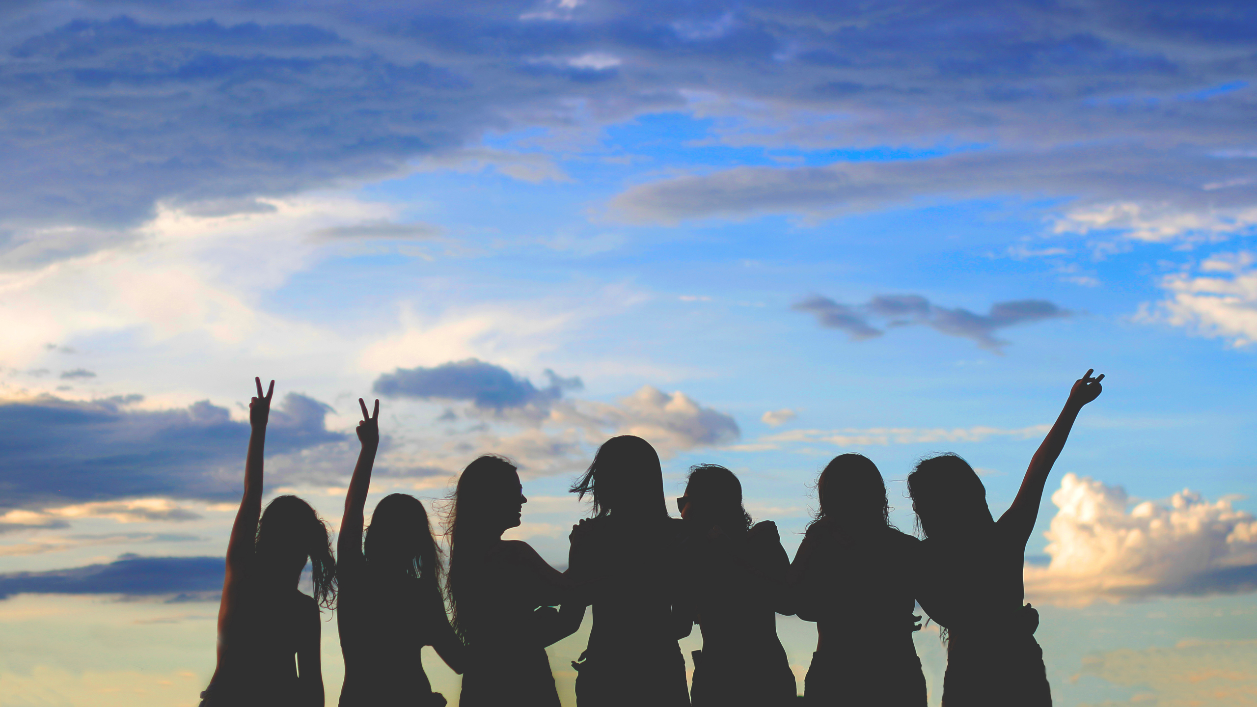 Silhouettes of women against a cloudy sky.