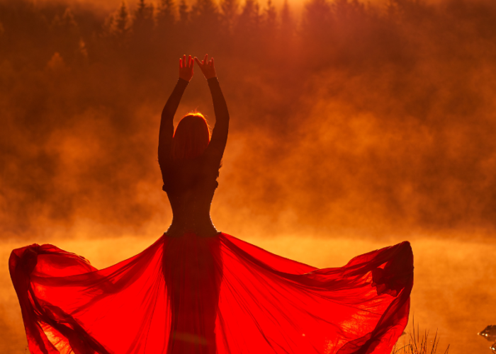 Silhouette of woman in red dress at sunrise.