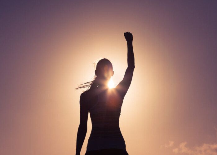 Silhouette of a woman raising her fist.