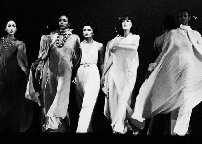 A group of women in white gowns on stage.