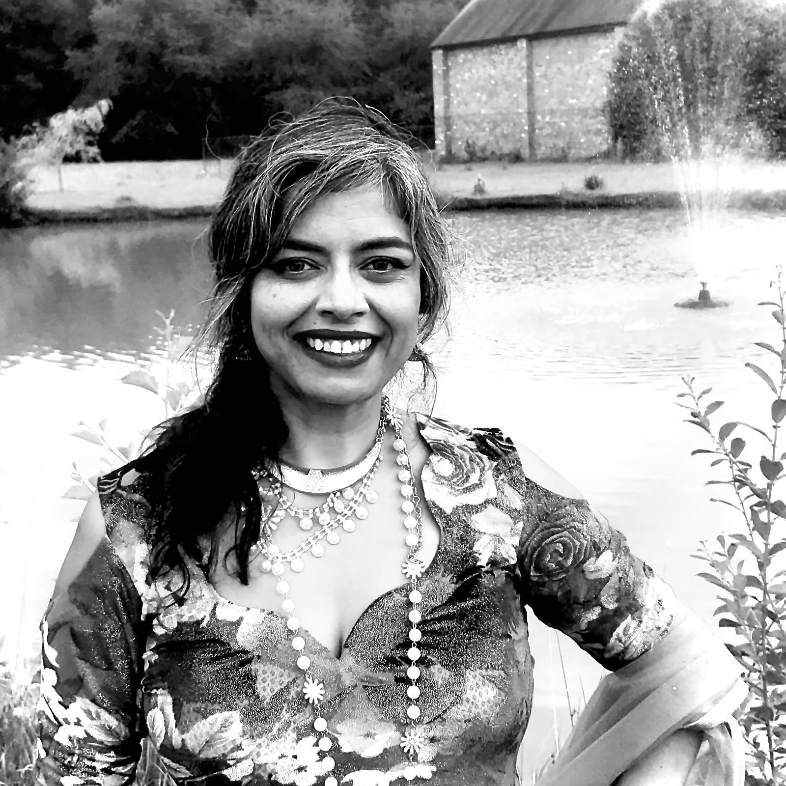 Woman wearing a floral top and jewelry.