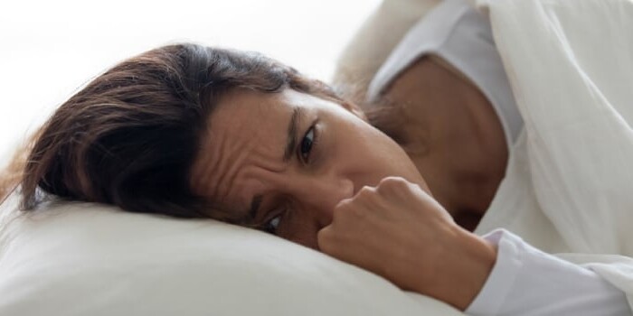 A woman laying in bed with her head on the pillow.